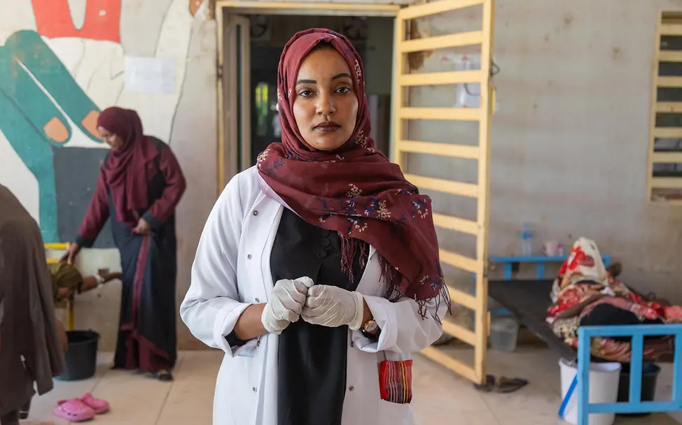 Eine junge Ärztin mit einem Kopftuch blickt in die Kamera