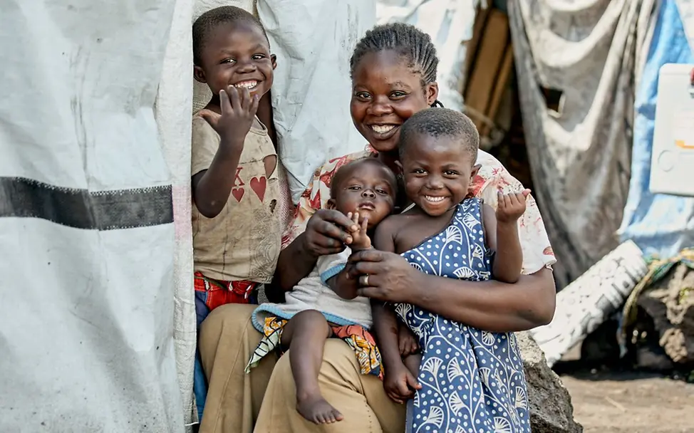 Kinder zeigen stolz, dass sie geimpft wurden. I © UNICEF/Shaka Vumbi Demokratische Republik Kongo: Kinder mit ihrer Mutter in einem Flüchtlingscamp.