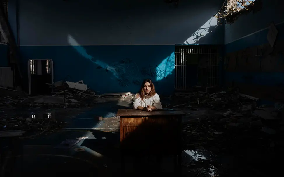 Kinder im Krieg: Daria sitzt an einem Schreibtisch in der Turnhalle ihrer zerstörten Schule in der Ukraine.