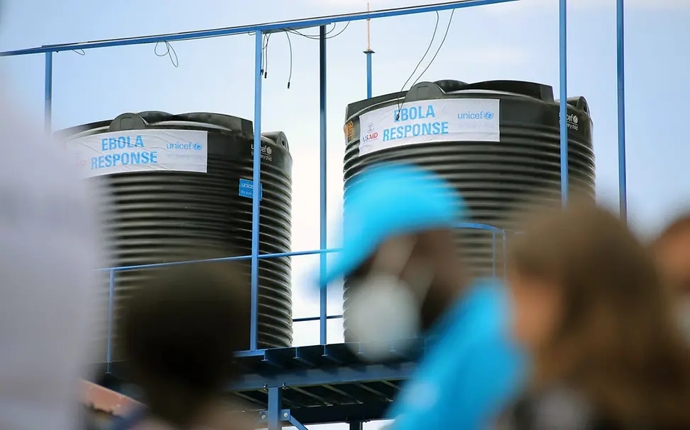 Ein UNICEF-Mitarbeiter in Uganda vor großen Wassertanks, die bei der Ebolabekämpfung helfen. | © UNICEF/Tibaweswa Ebola in Uganda: UNICEF unterstützt Ebolaregionen mit großen Wassertanks und anderen Hilfsgütern.