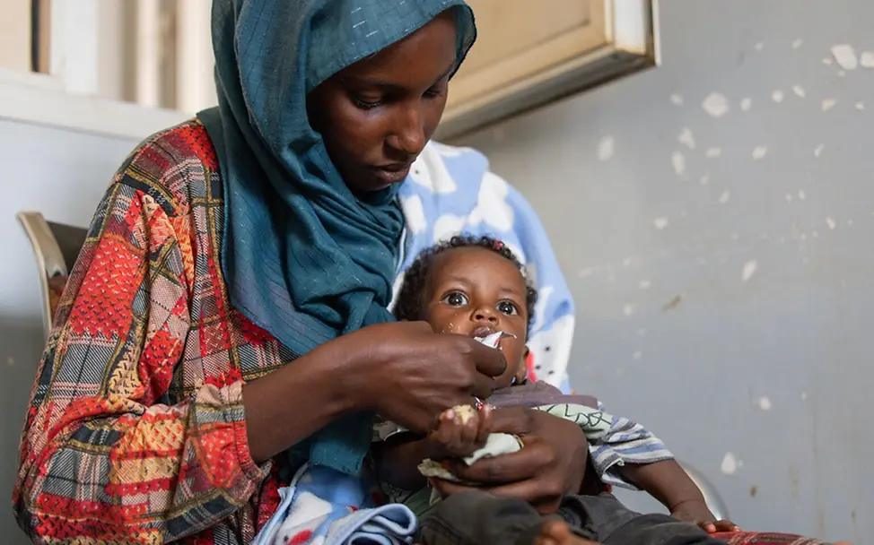 Eine Mutter füttert ihren sieben Monate alten Sohn mit therapeutischer Spezialnahrung. | © UNICEF/Elfatih Eine Mutter füttert ihren sieben Monate alten Sohn mit therapeutischer Spezialnahrung.