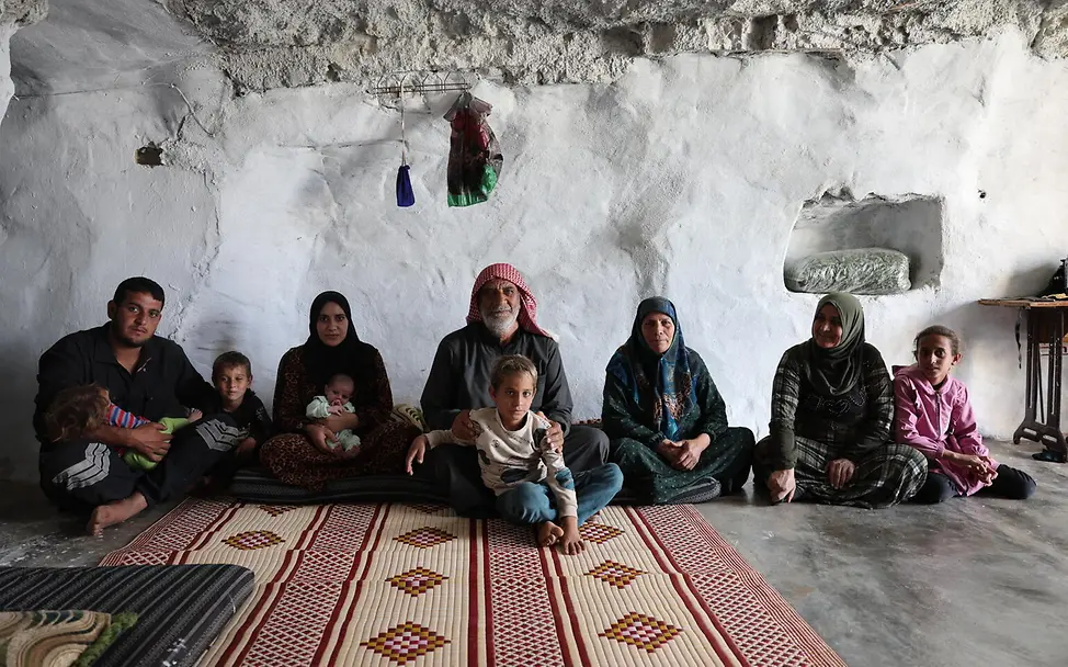 eine Familie sitzt auf dem Boden einer Höhle in der sie lebt