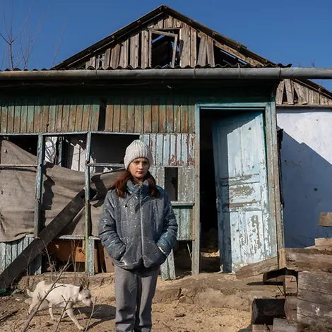 Alina (12) steht vor ihrem Wohnhaus, das im Krieg schwer beschädigt wurde | UNICEF/UNI739399/Filippov Ukraine-Krieg Verlauf: Alina steht vor ihrem beschädigten Haus