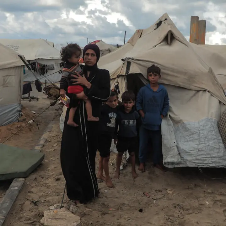 Maysaa steht mit ihren Kindern vor einem provisorischen Zelt