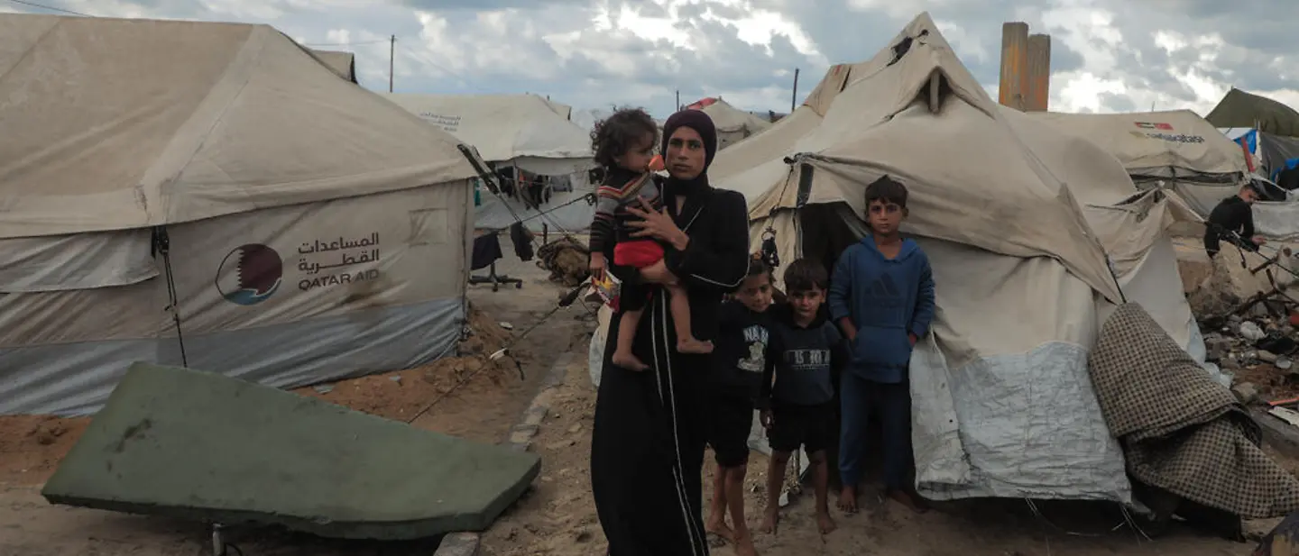 Maysaa steht mit ihren Kindern vor einem provisorischen Zelt