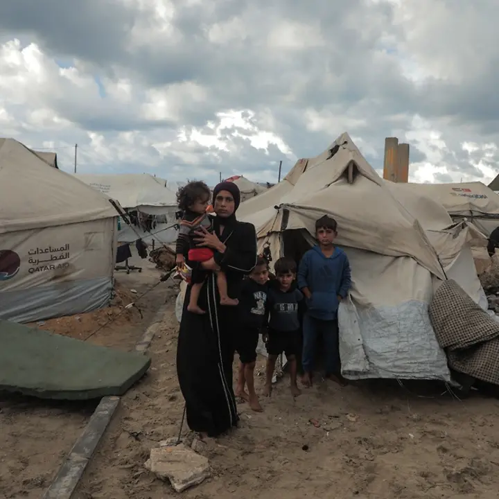 Maysaa steht mit ihren Kindern vor einem provisorischen Zelt