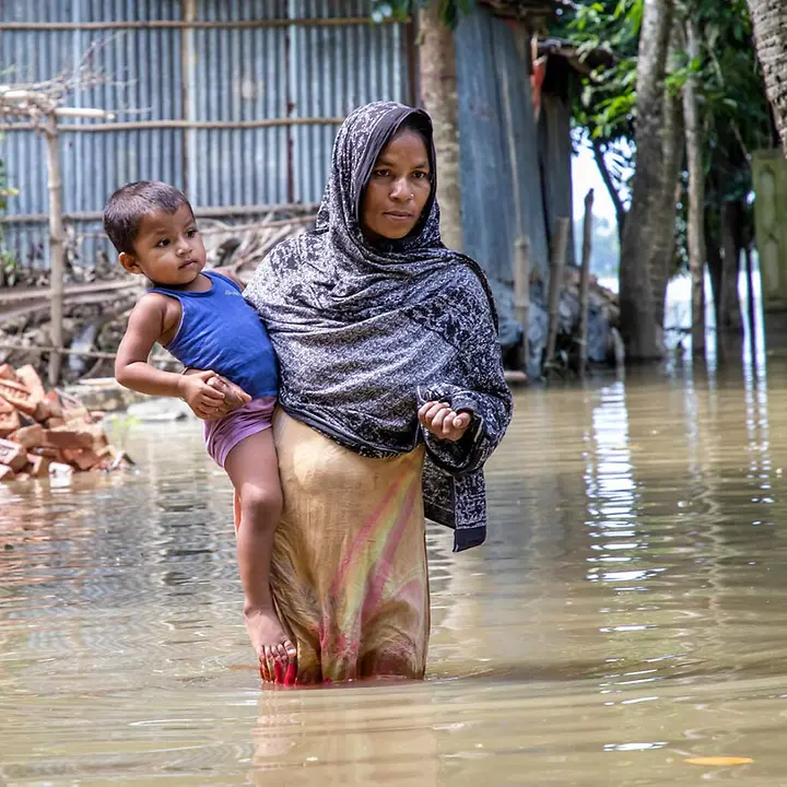 Monsun in Asien: Eine Mutter trägt ihr Kind durch hüfthohes Wasser | © UNICEF/Satu Monsun in Asien: Eine Mutter in Bangladesch trägt ihr Kind durch hüfthohes Wasser.