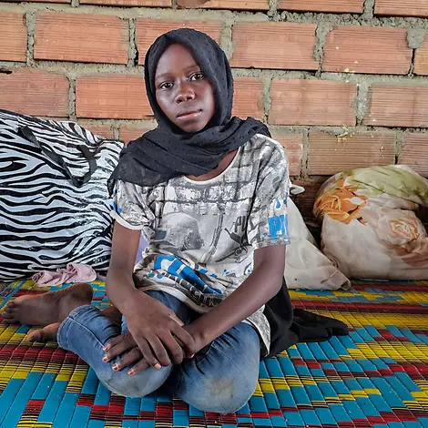 Ein Mädchen sitzt auf einer bunten Matte auf dem Boden