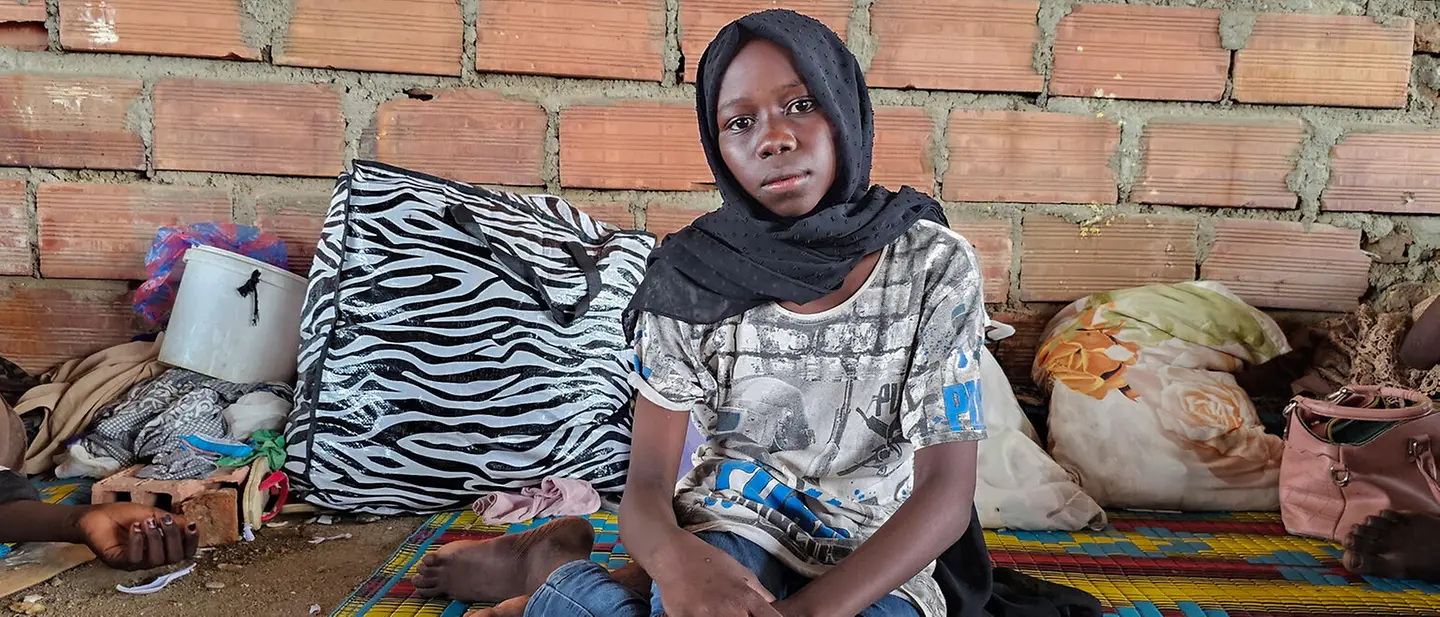 Ein Mädchen sitzt auf einer bunten Matte auf dem Boden