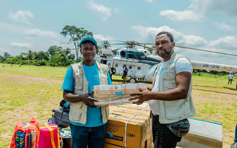 UNICEF-Mitarbeiter nehmen die eben eingeflogenen Hilfsgüter entgegen. | © UNICEF/Badimu Ebola Kongo: Impfstoffe und andere UNICEF-Hilfsgüter werden per Helikopter in die Ebolaregion gebracht.