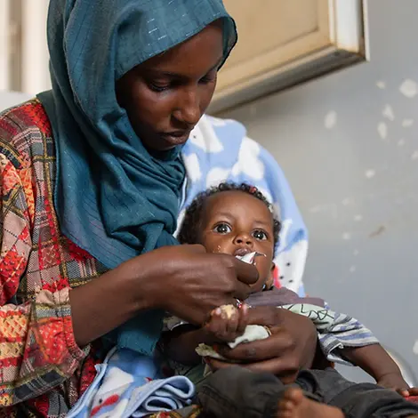 Hunger im Sudan: Naba füttert ihren Sohn Adnan mit Erdnusspaste