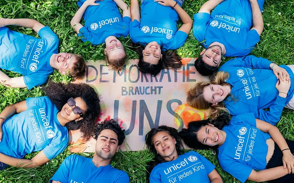 Was ist Demokratie einfach erklärt: Jugendliche vor einem Schild zum Thema Demokratie