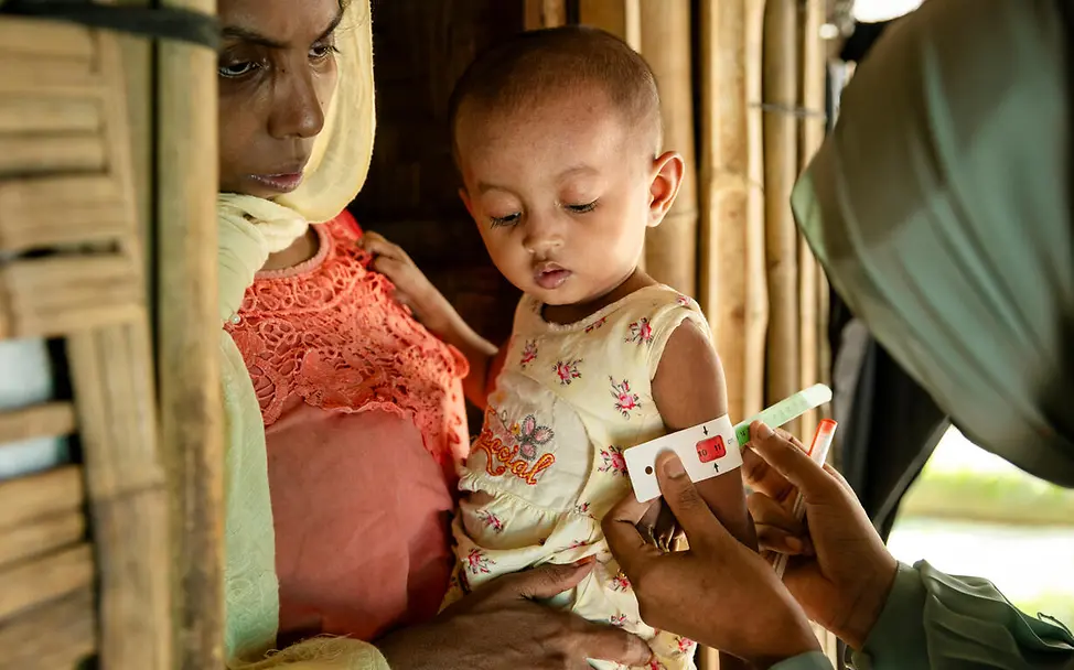 Rohingya Flüchtlingslager: Ein Kleinkind auf dem Arm seiner Mutter wird auf Mangelernährung getestet.  