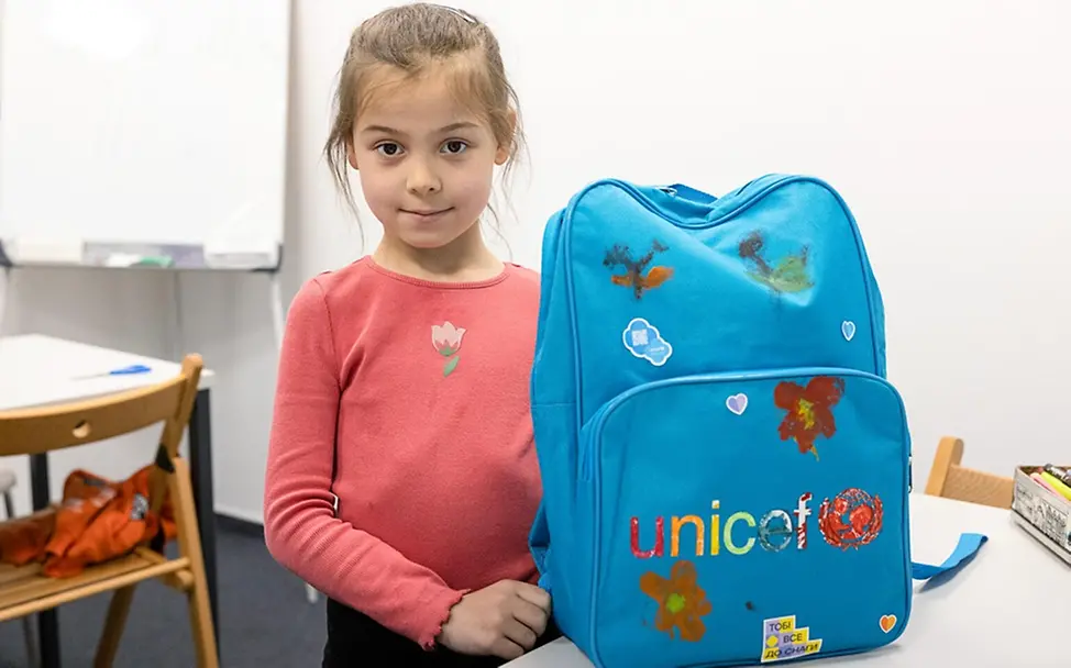 Gute Nachricht: Olha (7) zeigt stolz ihren blauen UNICEF-Schulrucksack.