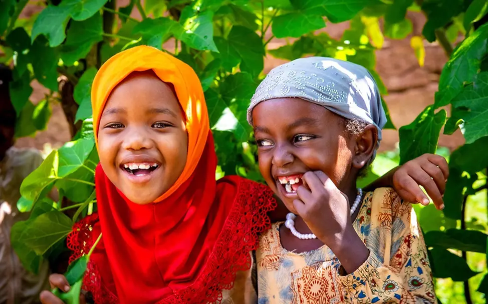 Kinderrechte für Kinder: Alle Kinder haben einen Anspruch darauf, gesund, in Frieden und ohne Hunger aufzuwachsen. Kinderrechte leicht erklärt: Zwei Mädchen lachen Arm in Arm.