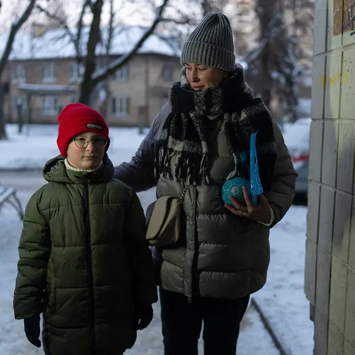Winter in der Ukraine: Ein Junge steht in Kiew mit seiner Mutter in einem Hauseingang | © UNICEF/Filippov Ukraine Krieg: Der Winter bringt die Kinder zusätzlich in Gefahr