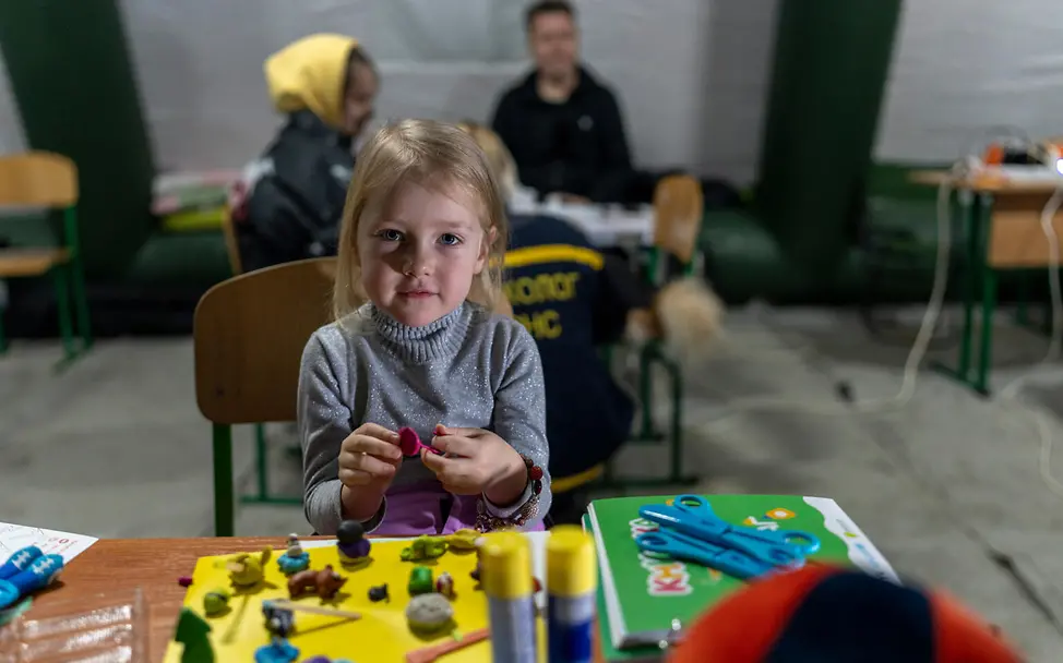 | © UNICEF/Filippov Ukraine Krieg: Ein Mädchen sitzt in einem beheizten Zelt und spielt.