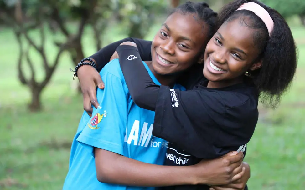 Rassismus einfach erklärt: Zwei Mädchen umarmen sich lachend.