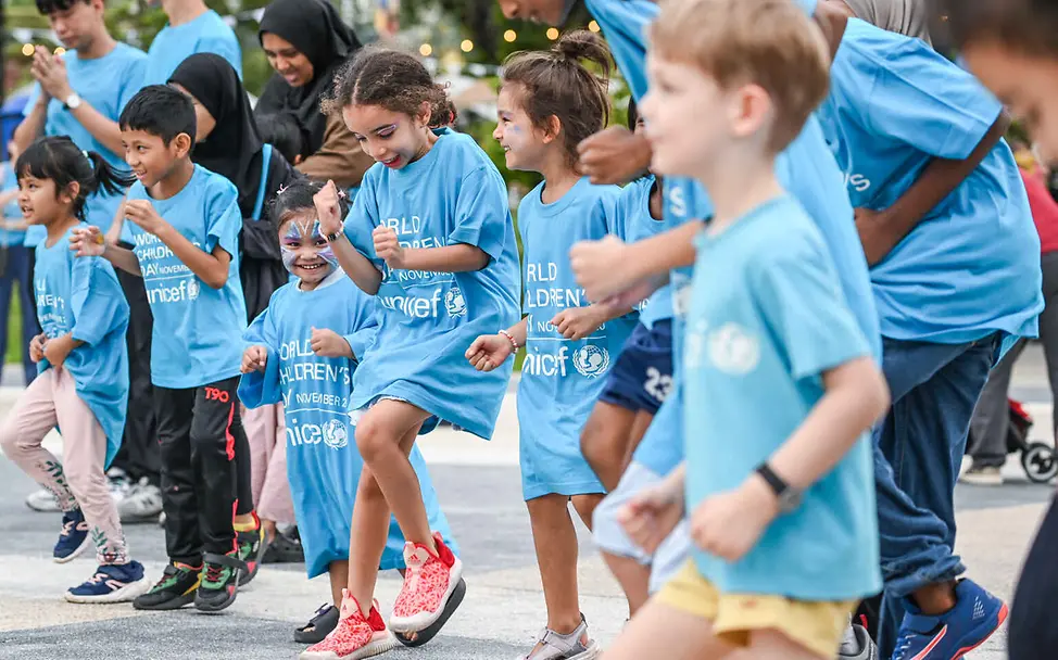Rassismus einfach erklärt: Kinder und Erwachsene in UNICEF-Shirts tanzen