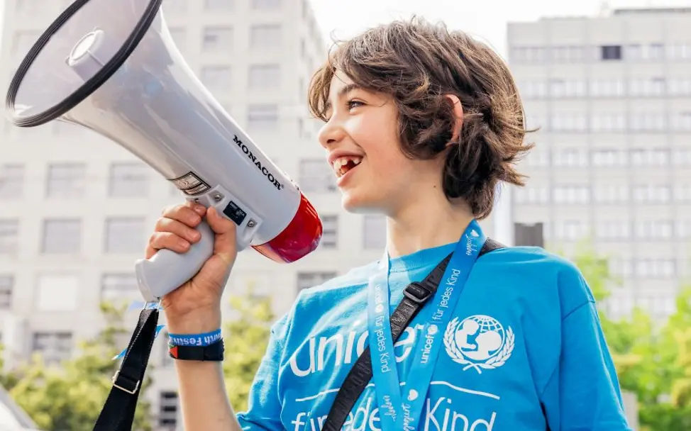 Rassismus einfach erklärt: Ein Junge im UNICEF-Shirt mit einem Megafon in der Hand.
