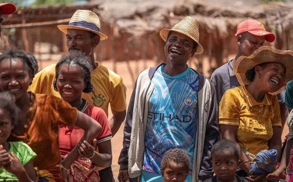 Menschenrechte einfach erklärt: Alle Menschen sind gleich und haben die gleichen Rechte. Menschenrechte einfach erklärt: Erwachsene und Kinder stehen lachend in einer Gruppe zusammen.