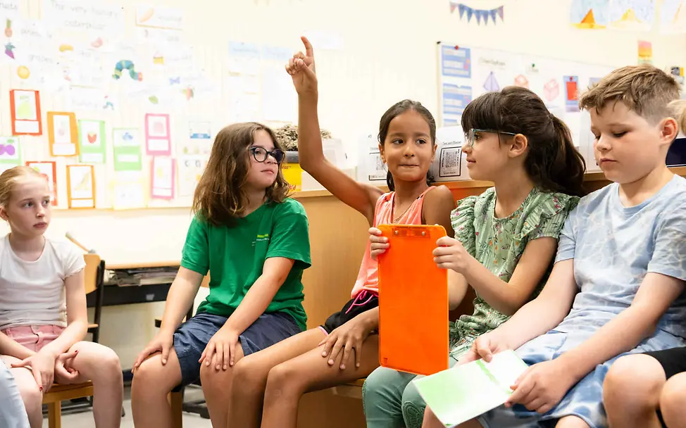 Menschenrechte einfach erklärt: Jeder Mensch darf frei sagen, was er oder sie denkt. Menschenrechte einfach erklärt: Kinder sitzen in einem Klassenraum und sprechen.
