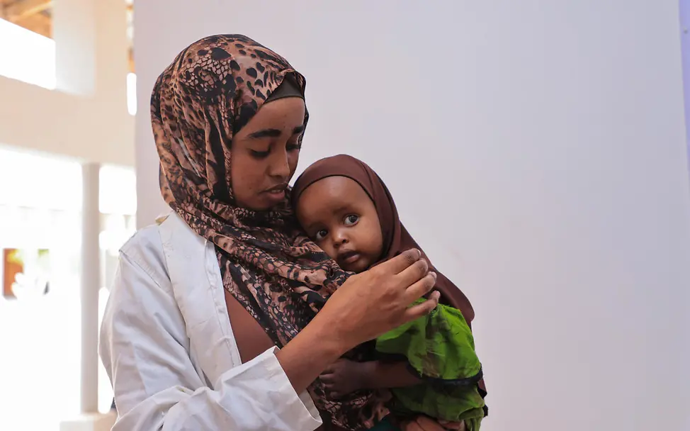 Eine Krankenschwester mit Kind auf dem Arm