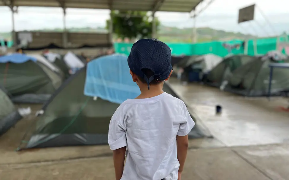 Ein Junge in Kolumbien vor einem Zelt