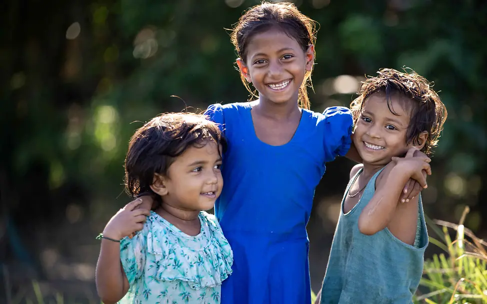Arsen im Trinkwasser: Drei Kinder umarmen sich lachend.