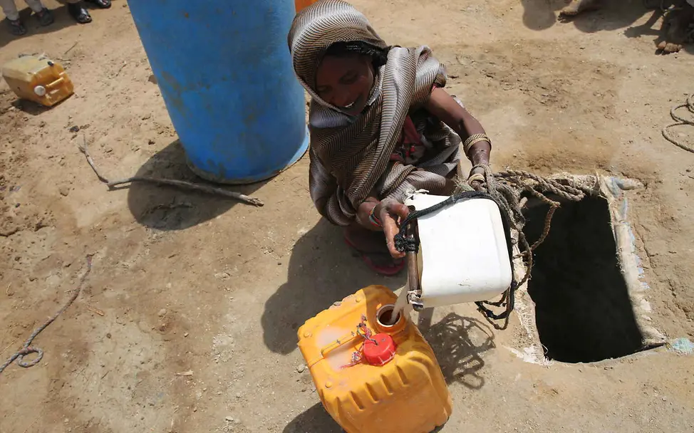 Südsudan Hungerkrise: Ein Kind holt Wasser aus einem Wasserloch im Boden.
