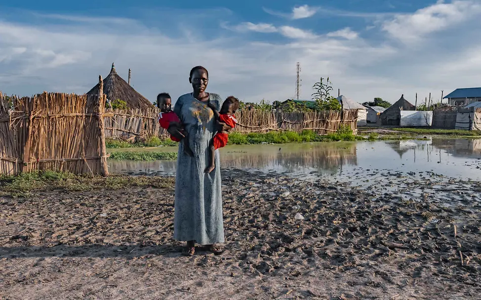 Südsudan Hungerkrise: Eine Mutter mit Zwillingen steht in ihrem überfluteten Dorf.