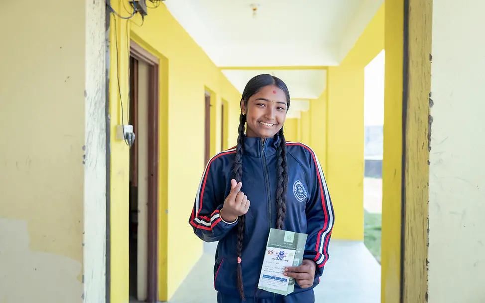 Gute Nachricht aus Nepal: Manisha hält ihre Impfkarte in der Hand und lacht.