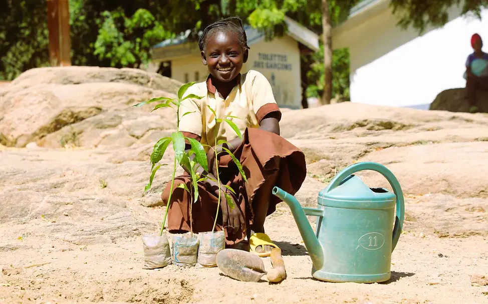 Was ist Klimaschutz: Wir alle können etwas tun, damit Kinder überall auf der Welt auch in Zukunft gut leben können. | © UNICEF/Beguel Klimaschutz einfach erklärt: Ein Mädchen mit Pflanzen und Gießkanne auf trockenem Boden.