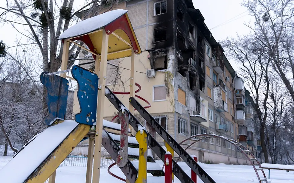 Ukraine: Ein Spielplatz vor einem zerstörten Gebäude
