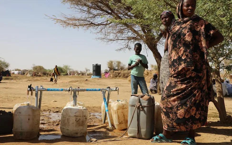 Sauberes Wasser: Eine Mutter mit Kindern füllt Wasserkanister an einer Wasserleitung.