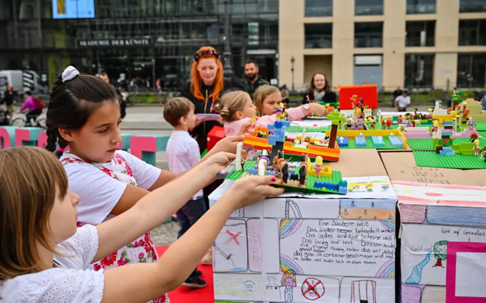 Weltkindertag Kindern erklären: Der Weltkindertag hat jedes Jahr ein besonderes Motto. | © UNICEF/PaulaGVidal Weltkindertag einfach erklärt: Kinder präsentieren ihre Bauwerke aus Lego.