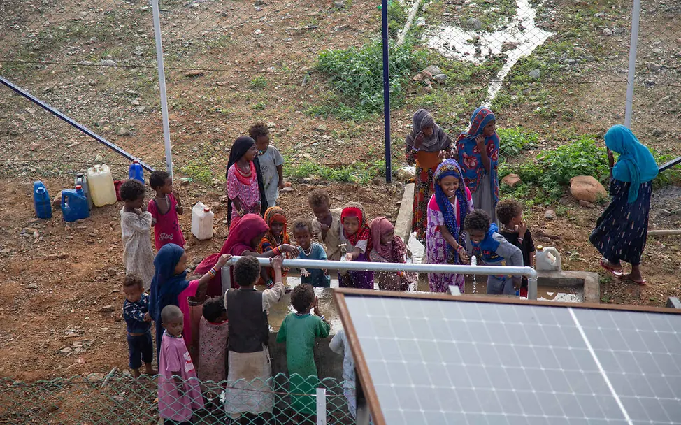 Wasserkrise: UNICEF unterstützt den Bau von solarbetriebenen Wassersystemen. © UNICEF/Elfatih Wasserknappheit weltweit: Menschen stehen um eine solarbetriebene Wasserpumpe.