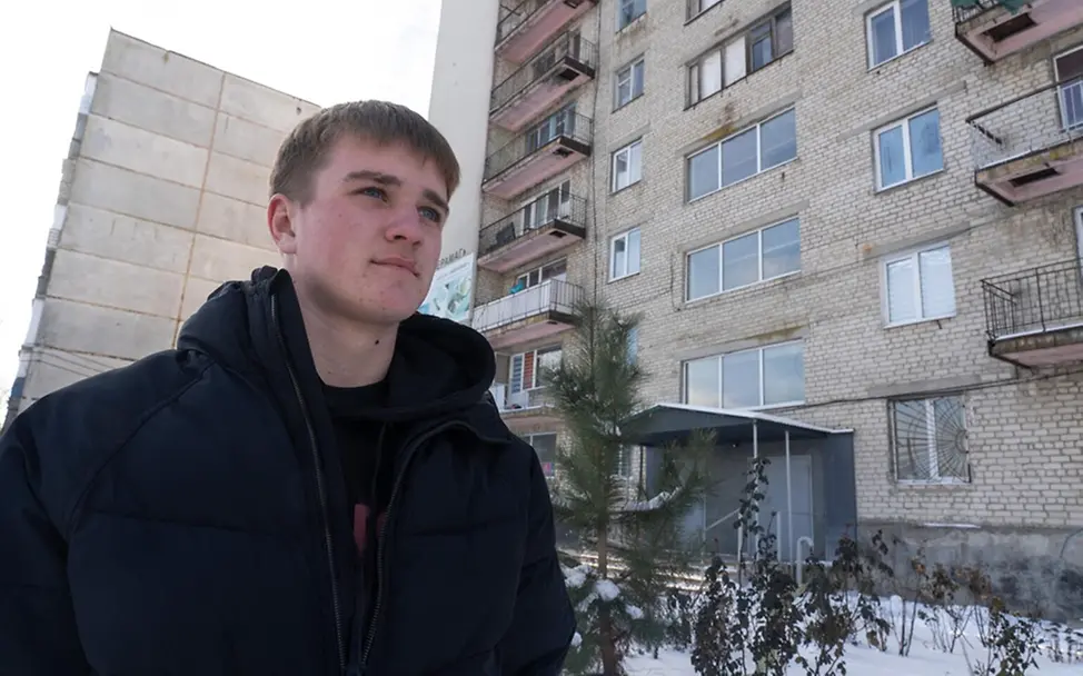 Ukraine Krieg: Ein Jugendlicher in Charkiw vor einem großen Wohnhaus. 