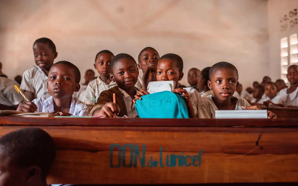 Kriegskinder im Kongo: Schüler an Schultischen schauen in die Kamera.