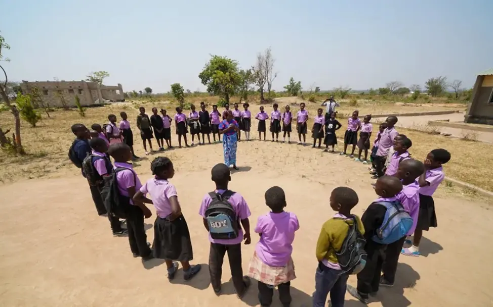 Schüler*innen mit ihrer Lehrerin auf dem Schulhof der Lupili Grundschule.