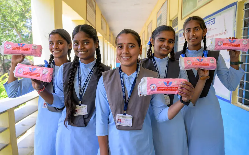 Was ist Periodenarmut: Schülerinnen posieren mit Binden in ihrer Schule. 