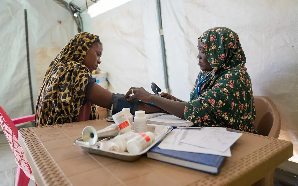 Eine Frau nimmt den Blutdruck einer anderen Frau