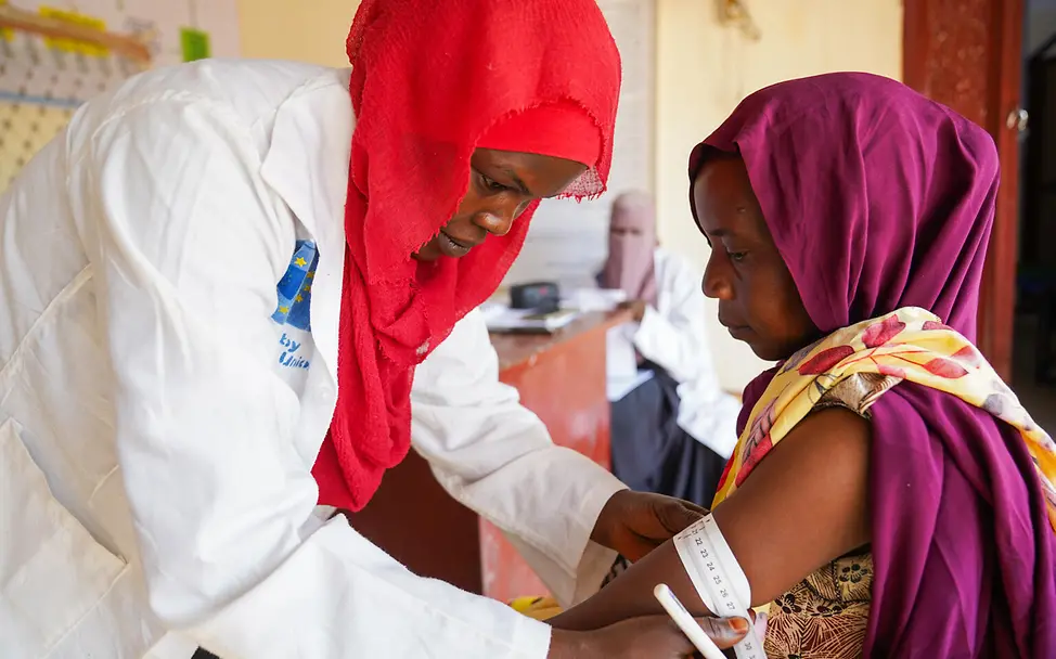 Frau misst Oberarmumfang einer anderen Frau