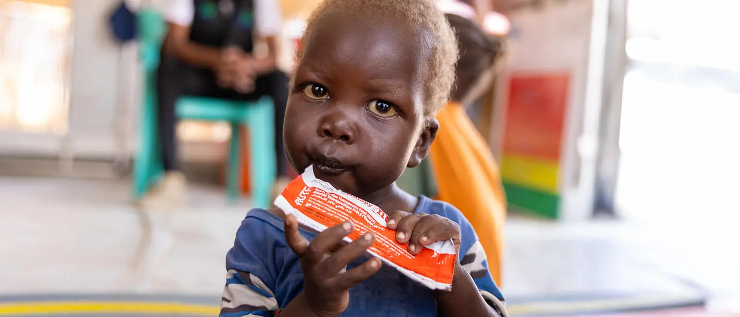 Ein kleiner Junge mit Erdnusspaste in der Hand