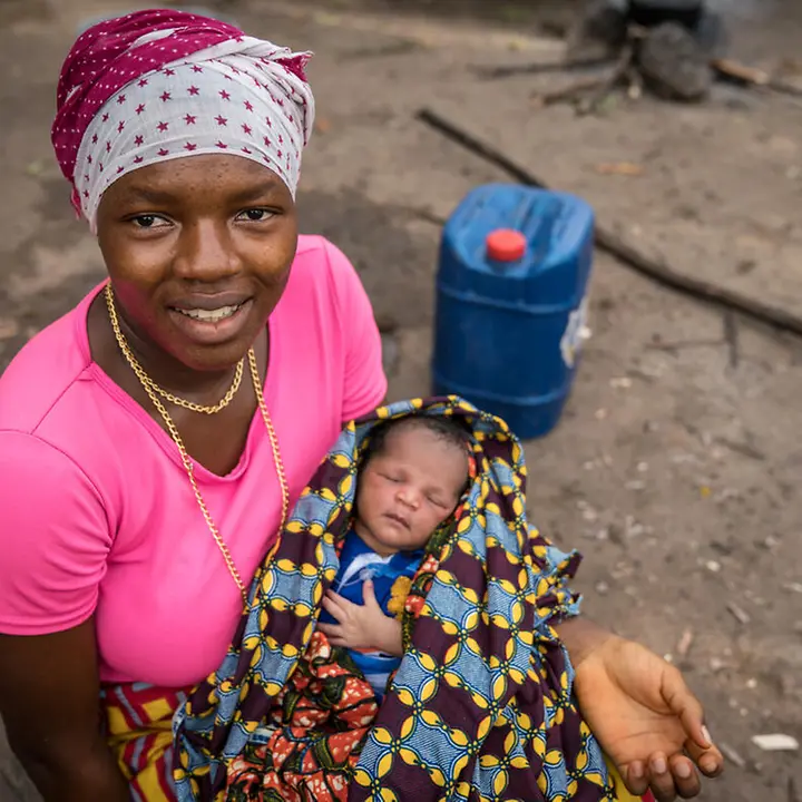 Geburten in Sierra Leone: Ohne medizinische Versorgung ist das Leben von Müttern und Babys in Gefahr. | © UNICEF/Duff Kindersterblichkeit Sierra Leone: Eine Mutter mit einem Neugeborenen auf dem Arm schaut in die Kamera.