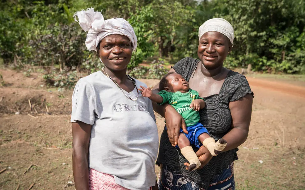 Kindersterblichkeit Sierra Leone: Die lokalen Gesundheitshelfer*innen können bei Schwierigkeiten schnell reagieren. | © UNICEF/Duff/VII Photo Kindersterblichkeit Sierra Leone: Eine Gesundheitshelferin posiert mit einer Mutter und ihrem Baby.