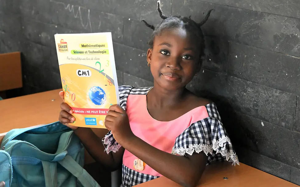 UNICEF versorgt Schulen in der Elfenbeinküste mit Lehrmaterialien und Schulmöbeln | © UNICEF/Dejongh Bildung für die Elfenbeinküste: Ein Schulkind zeigt sein Lernheft in die Kamera.