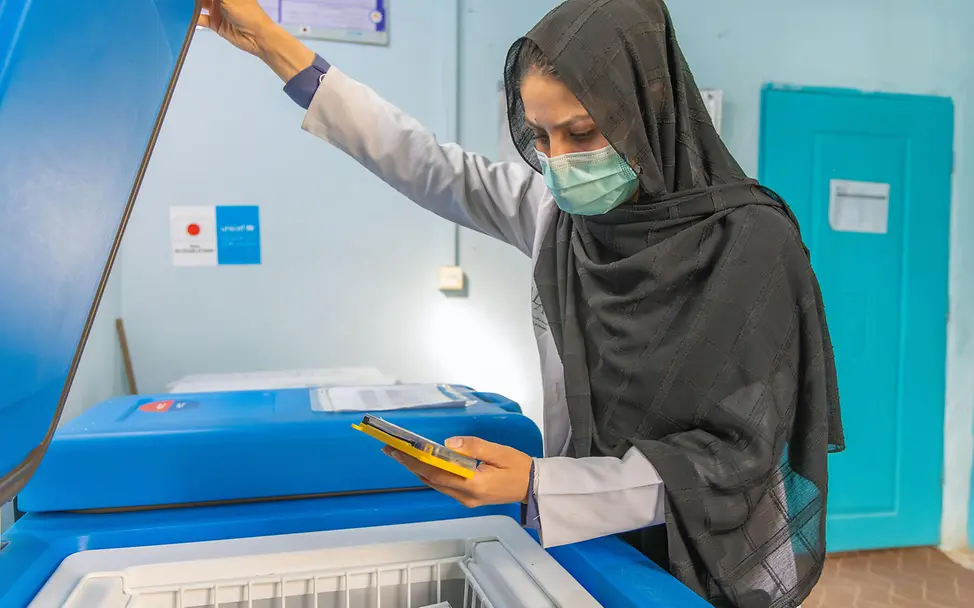 UNICEF stellt solarbetriebene Kühlschränke bereit, um Impfstoffe sicher zu lagern. | © UNICEF/Khayyam Impfen einfach erklärt: Eine Gesundheitshelferin prüft die Temperatur in einem Kühlschrank.