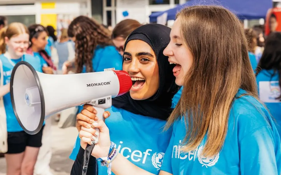 Teilnehmende des UNICEF-YouthFestivals in Mannheim. Die Stadt ist “Kinderfreundliche Kommune” | © UNICEF/Stroisch Jugendliche in UNICEF-T-Shirts nutzen ein Megafon bei einem Event draussen.