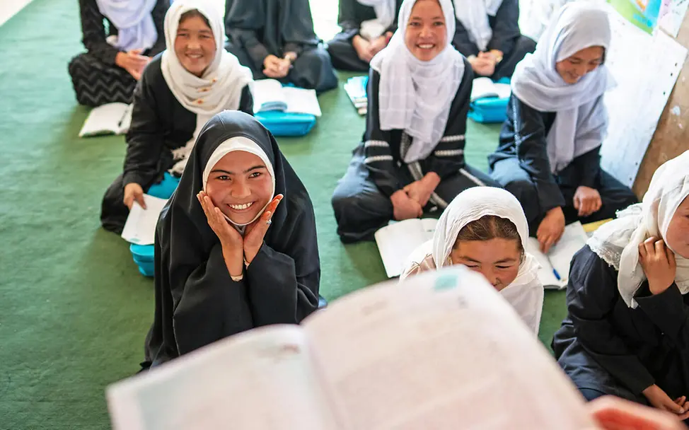 Viele Mädchen in Afghanistan sind seit Jahren nicht zur Schule gegangen. | © UNICEF/Naftalin Bildung in Afghanistan: Mädchen sitzen in der Schule am Boden und schauen auf ihre Lehrerin.